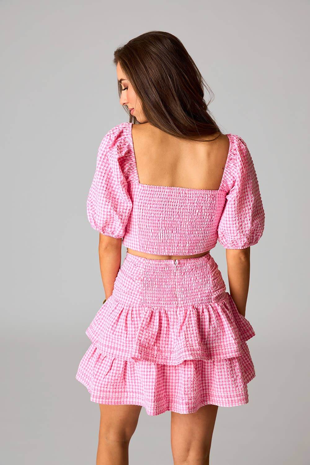 Pink gingham matching set with puff sleeve crop top and tiered ruffle mini skirt – stylish feminine outfit.